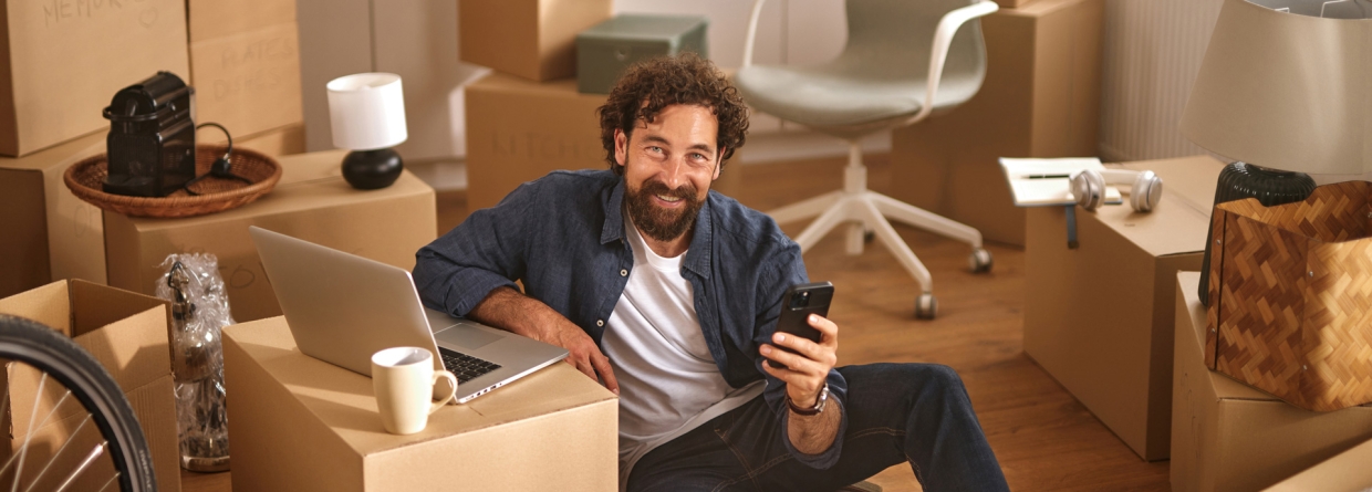 Iemand zit op de grond, omringd door kartonnen dozen in een pas verhuisd huis.